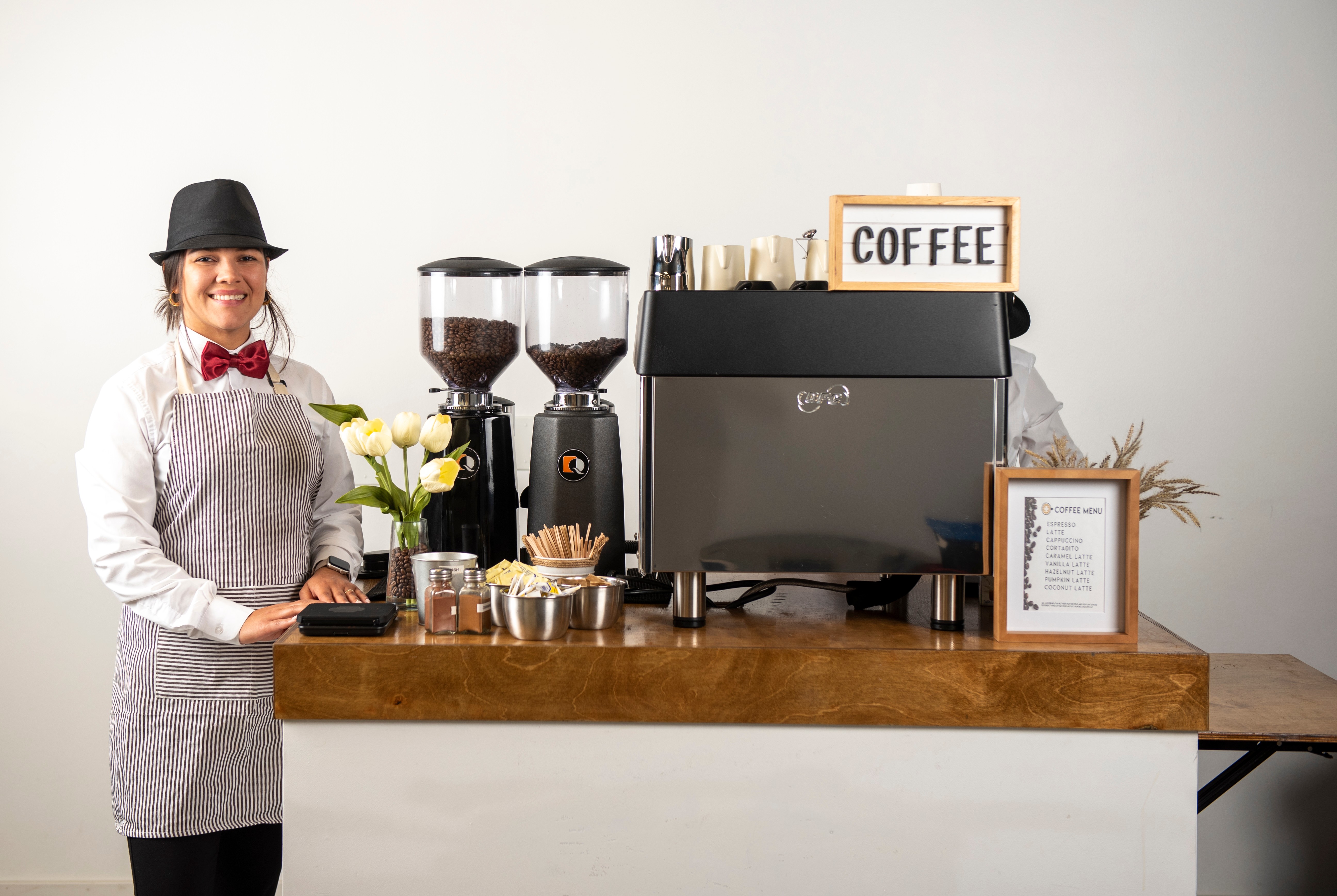 Professional female barista standing beside complete coffee station with premium equipment