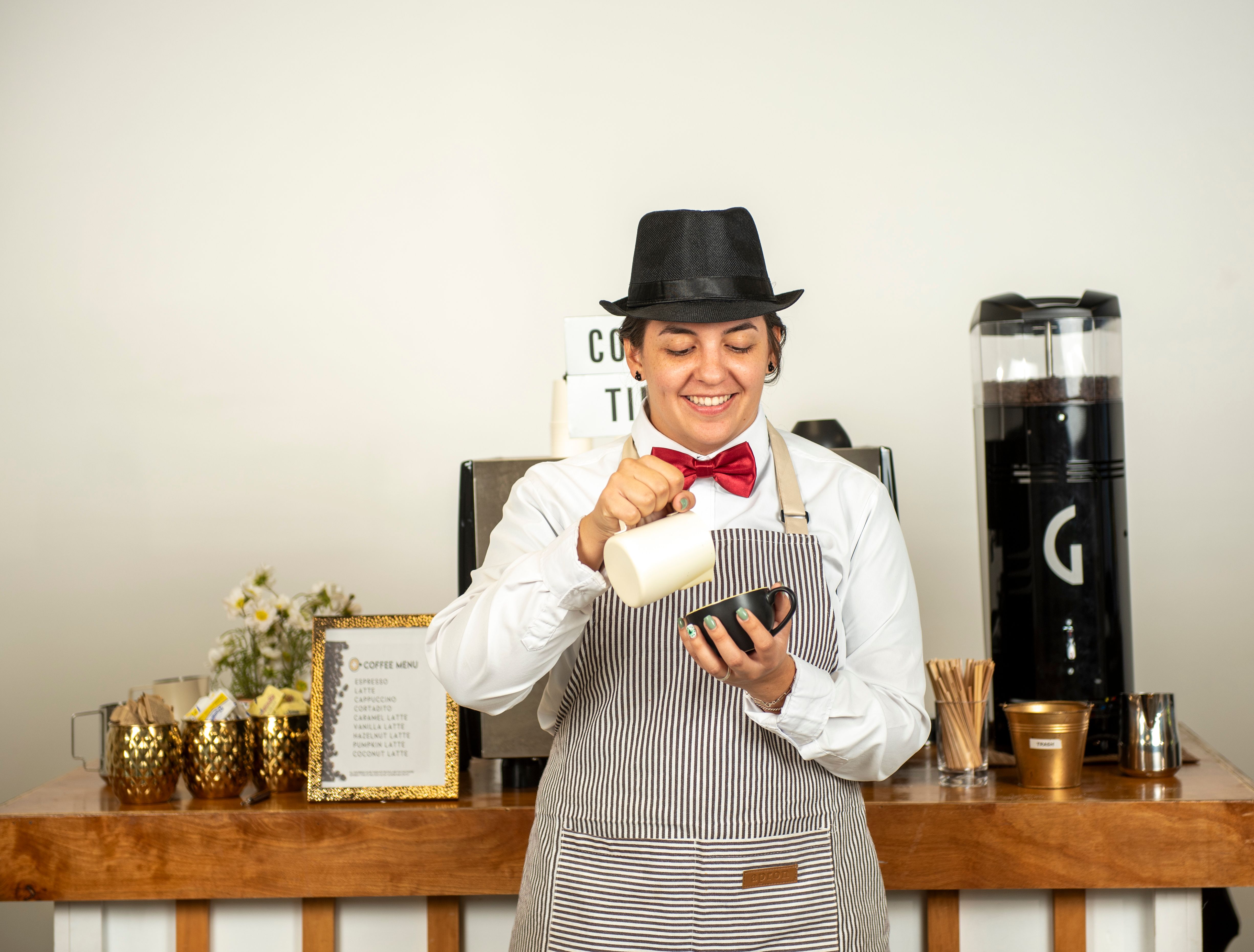 Smiling female barista preparing milk for coffee with professional equipment